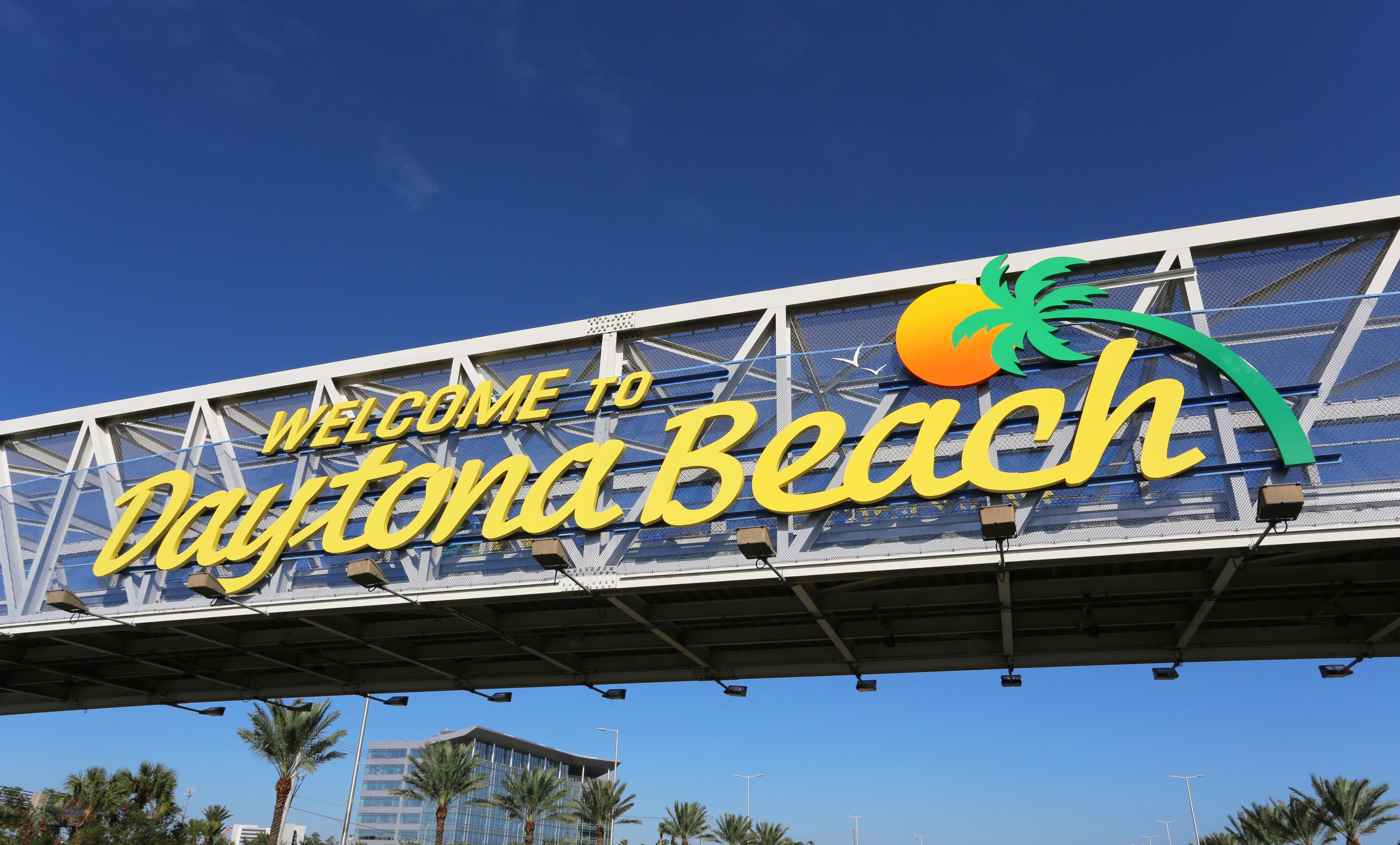Photo shows sign on a bridge that states "Welcome to Daytona Beach" with a Palm tree.