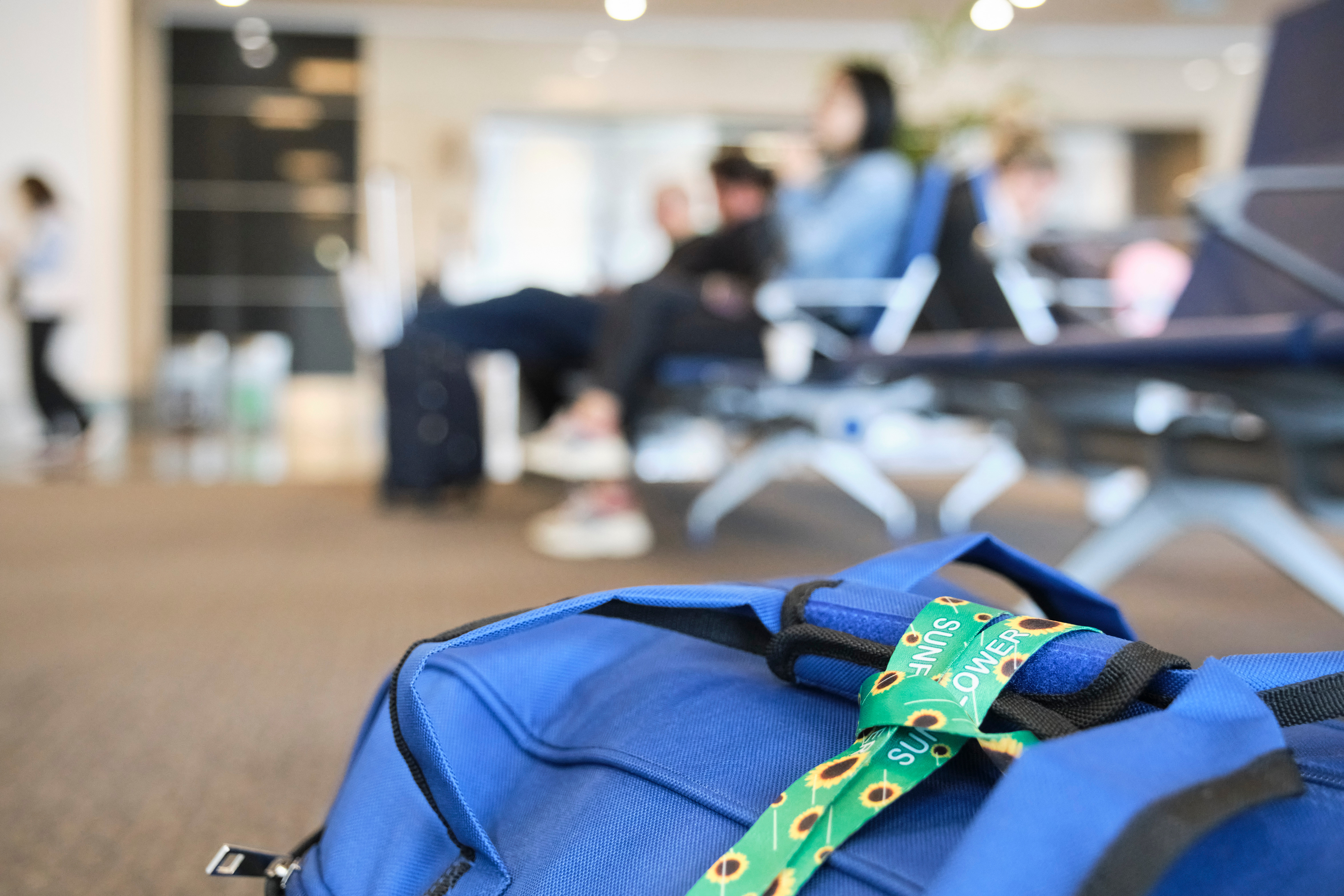 A bag on the floor at an airport gate with a Sunflower Network Lanyard attached to it