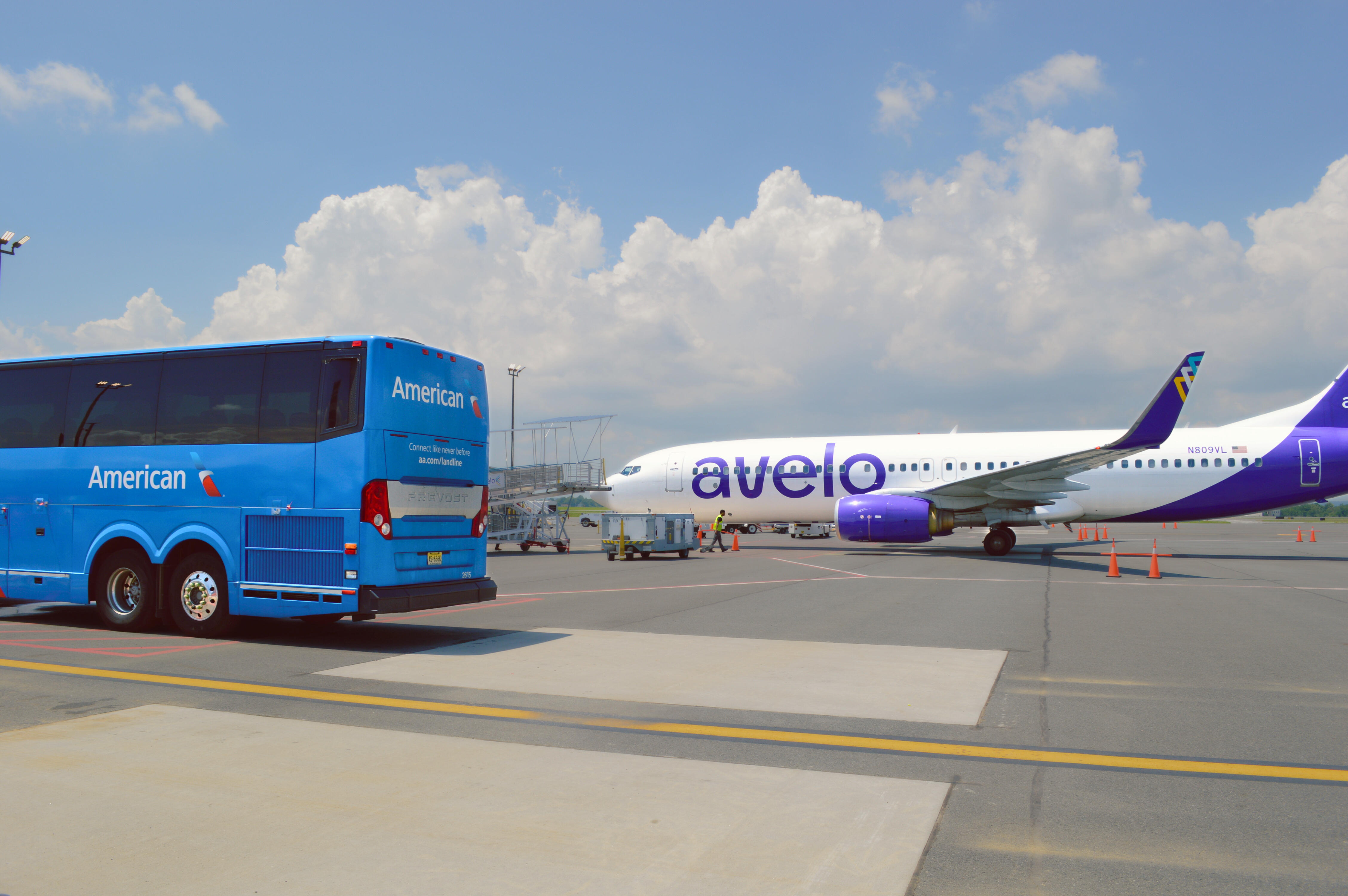 American Airlines Luxury Motorcoach and Avelo Airlines plane on a sunny day at ILG