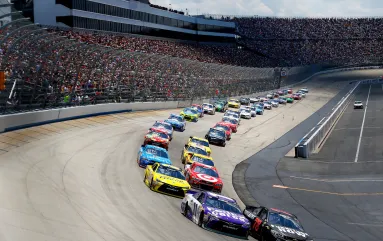 NASCAR drivers race around a bend at Dover Motor Speedway