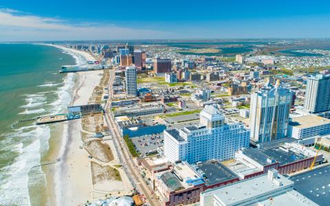 Photo shows aerial view of a beachfront city with various buildings and boardwalks along the beach. 