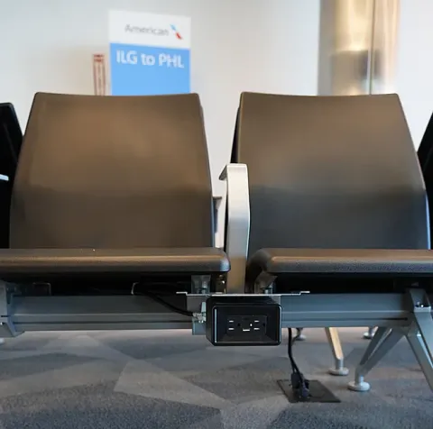 Wlmington Airport ILG seating in the gate hold room includes outlets in each row to easily charge devices