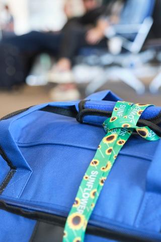 A bag on the floor at an airport gate with a Sunflower Network Lanyard attached to it