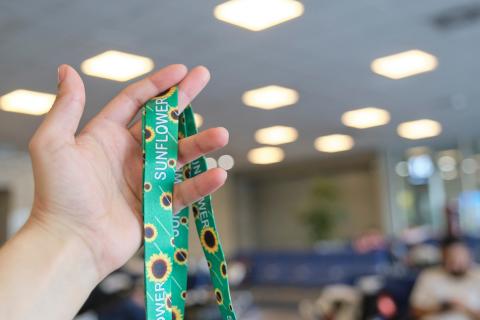 A hand raised in the air in an airport holding a Sunflower Network lanyard